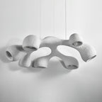 Clérachic pendant seen from slightly below on a light grey backdrop, its white arms switched off and openings facing down.