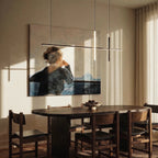 Clérachic pendant light in black hung over a dark wood dining table beside a framed portrait painting.
