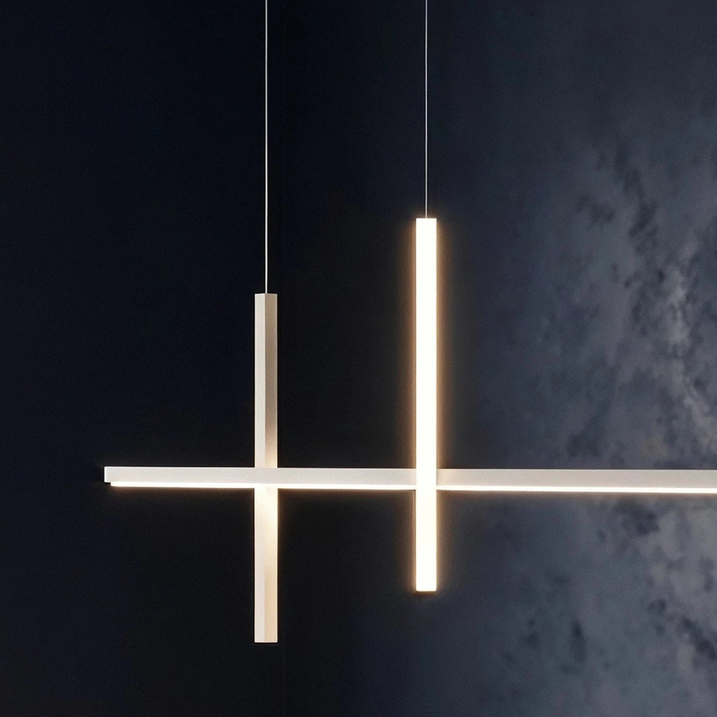Close-up of the Clérachic pendant light in white, both vertical bars glowing warm against a dark textured wall.
