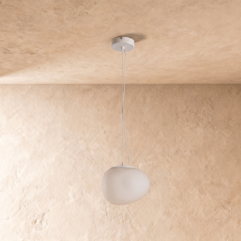 Clérachic irregular white pebble pendant in a soft matte frosted finish, hung low against limewashed plaster