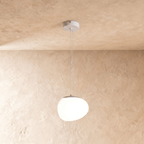 Clérachic organic white pendant with a lit opal shade, a grey cap and two slim wires from a white canopy
