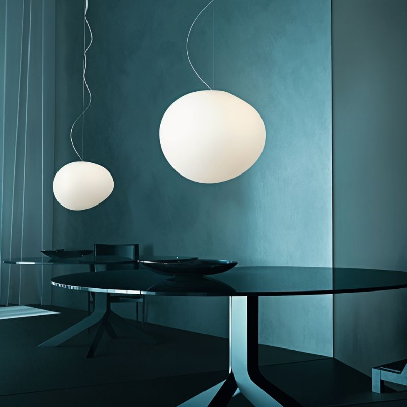 Clérachic two white pebble pendants in different sizes over a dark glass dining table against teal walls