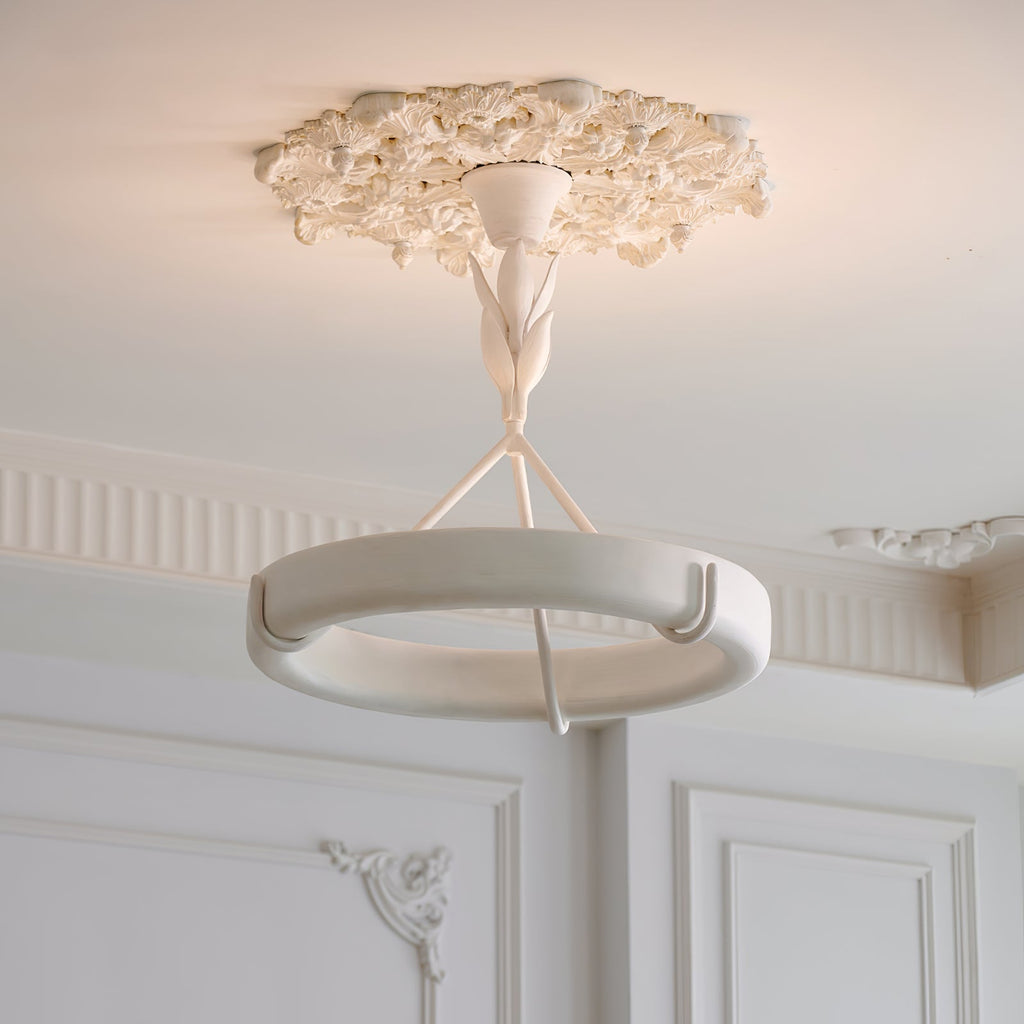 This Clérachic ceiling light hangs from a floral plaster rose, with panelled white walls and moulded cornices behind.