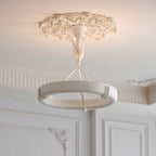 This Clérachic ceiling light hangs from a floral plaster rose, with panelled white walls and moulded cornices behind.