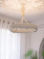 Warm light glows around the plaster ring of this Clérachic ceiling light, with a lace-edged ceiling rose and sheer curtains beside it.