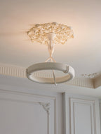 Clérachic ceiling light seen from a distance, its ring below a plaster rose in a room with white panelled walls.