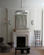 Clérachic ceiling light high in a panelled room, above a fireplace with a carved relief panel and a ladder-back chair.