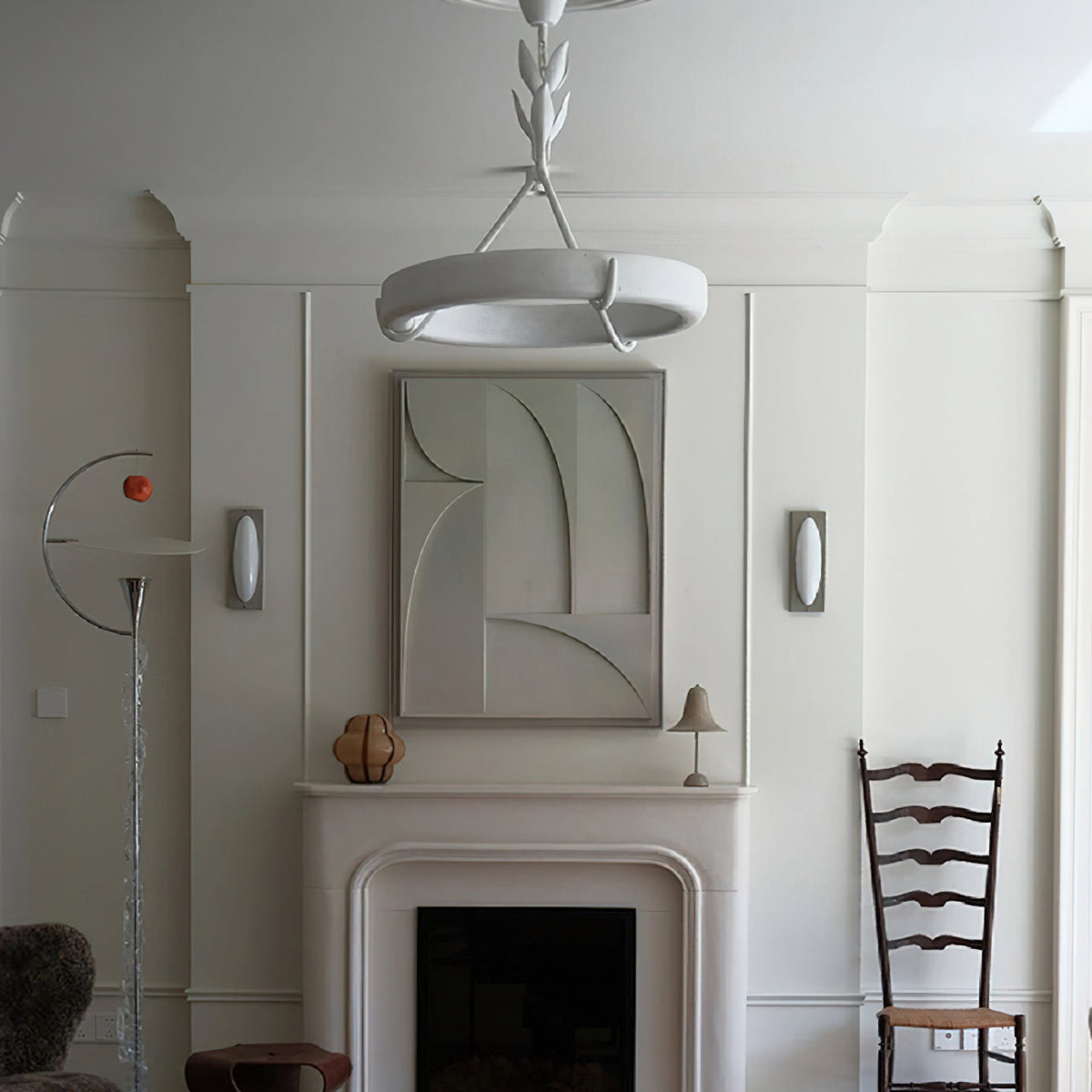 Closer crop of the same fireplace room, this Clérachic ceiling light hanging above a white mantel and a relief artwork.