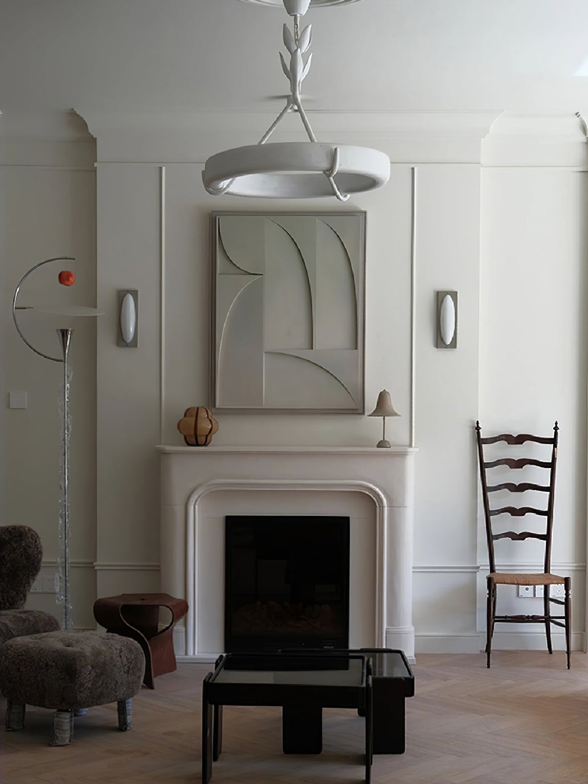 This Clérachic ceiling light seen from below in a tall room, above a white fireplace with a relief panel and a woolly stool.