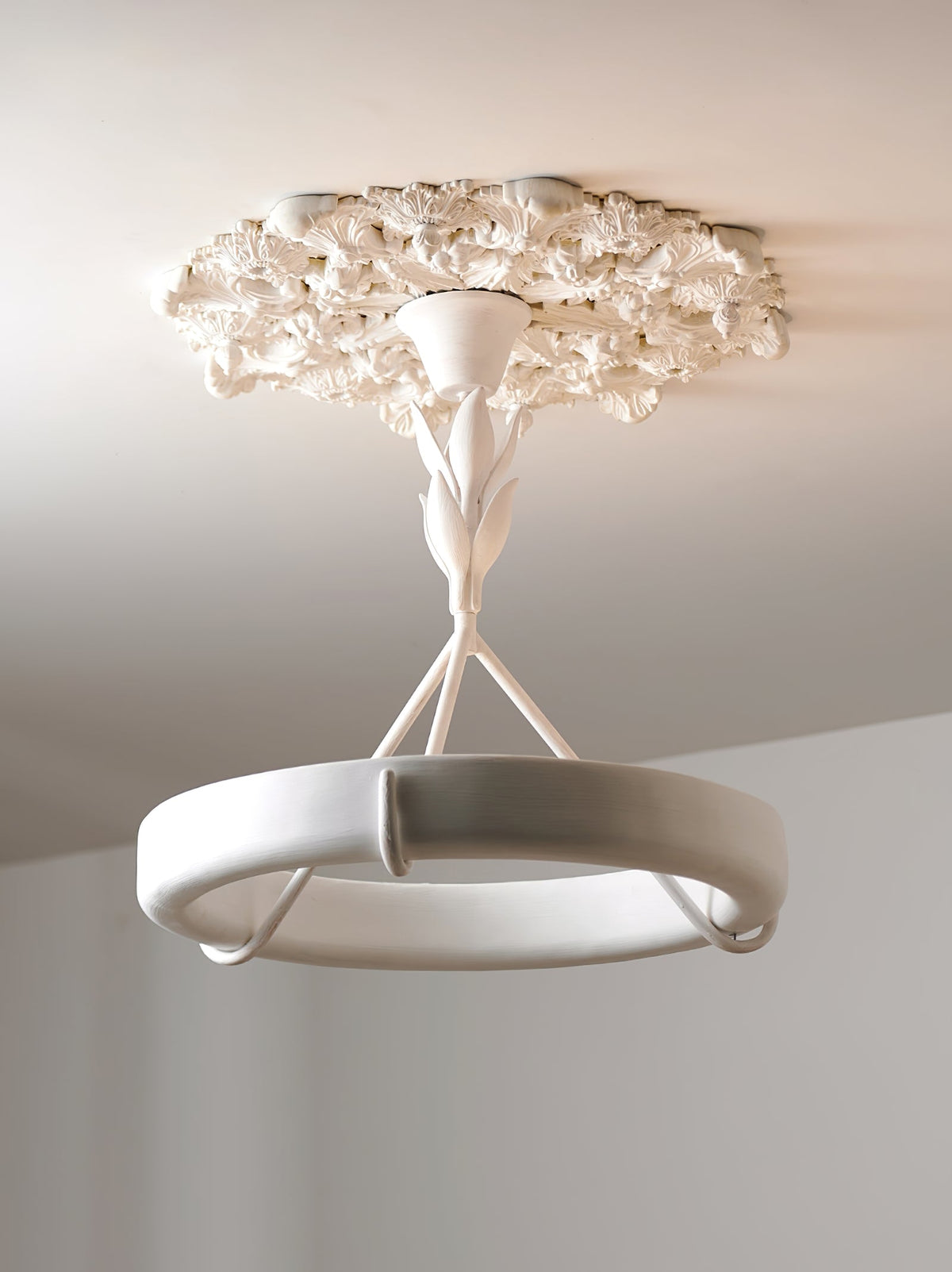 Looking up at this Clérachic ceiling light, its leaf stem rising to a thick plaster rose on a plain ceiling.