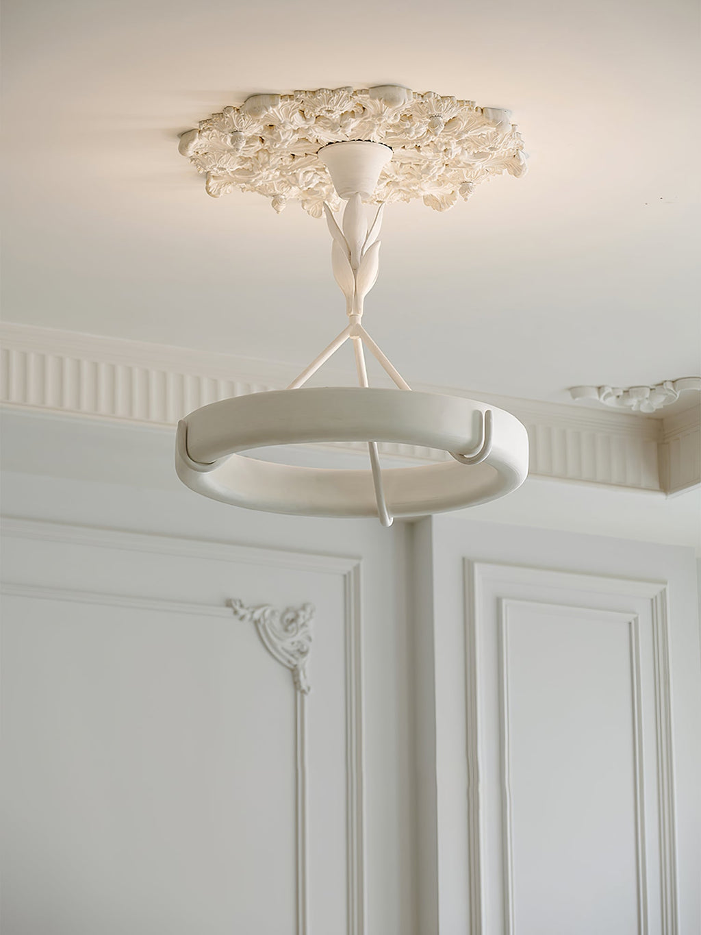 Clérachic ceiling light under a small plaster rose, with a panelled wall and a decorative corner moulding in the background.
