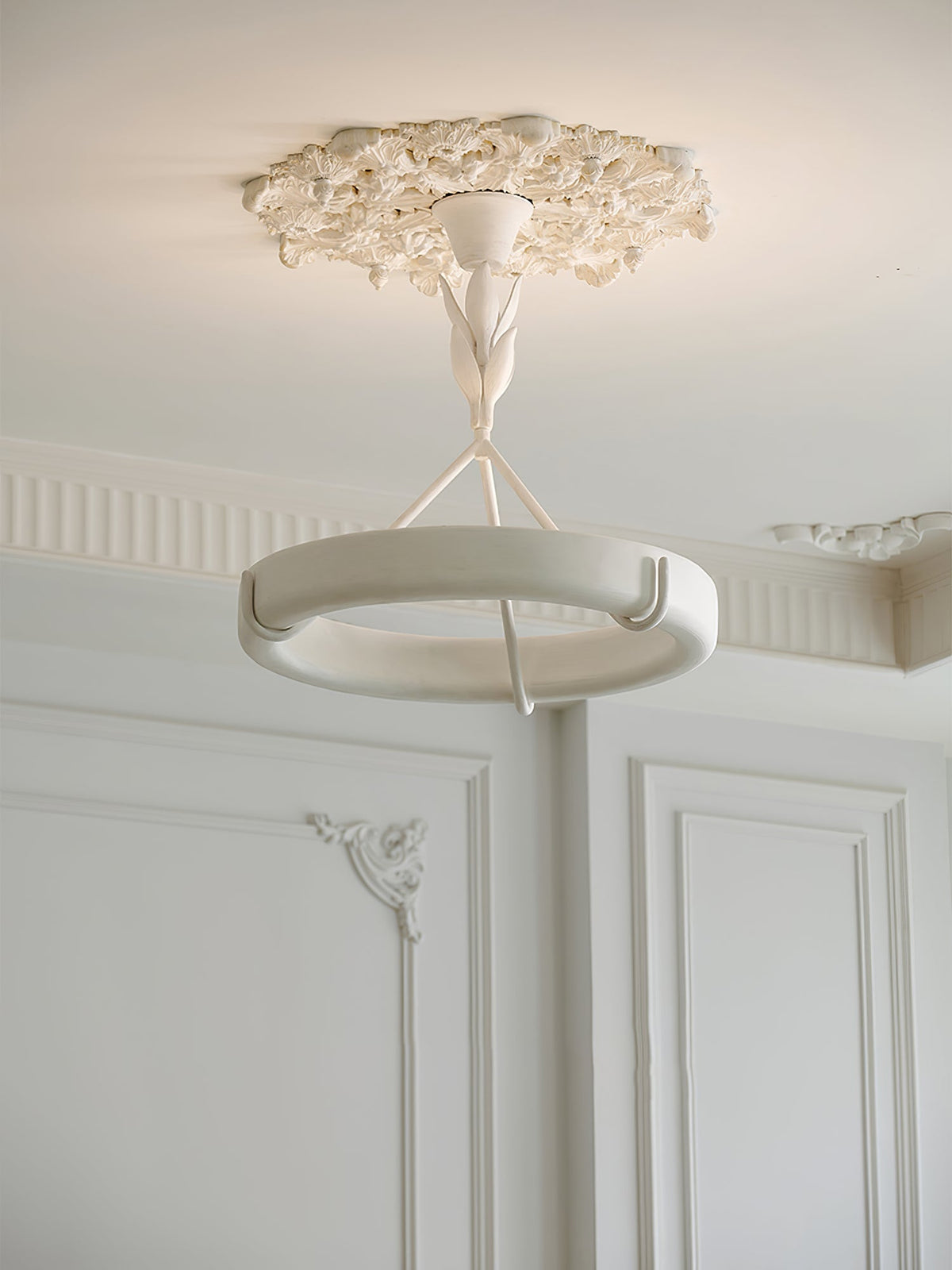 Clérachic ceiling light under a small plaster rose, with a panelled wall and a decorative corner moulding in the background.
