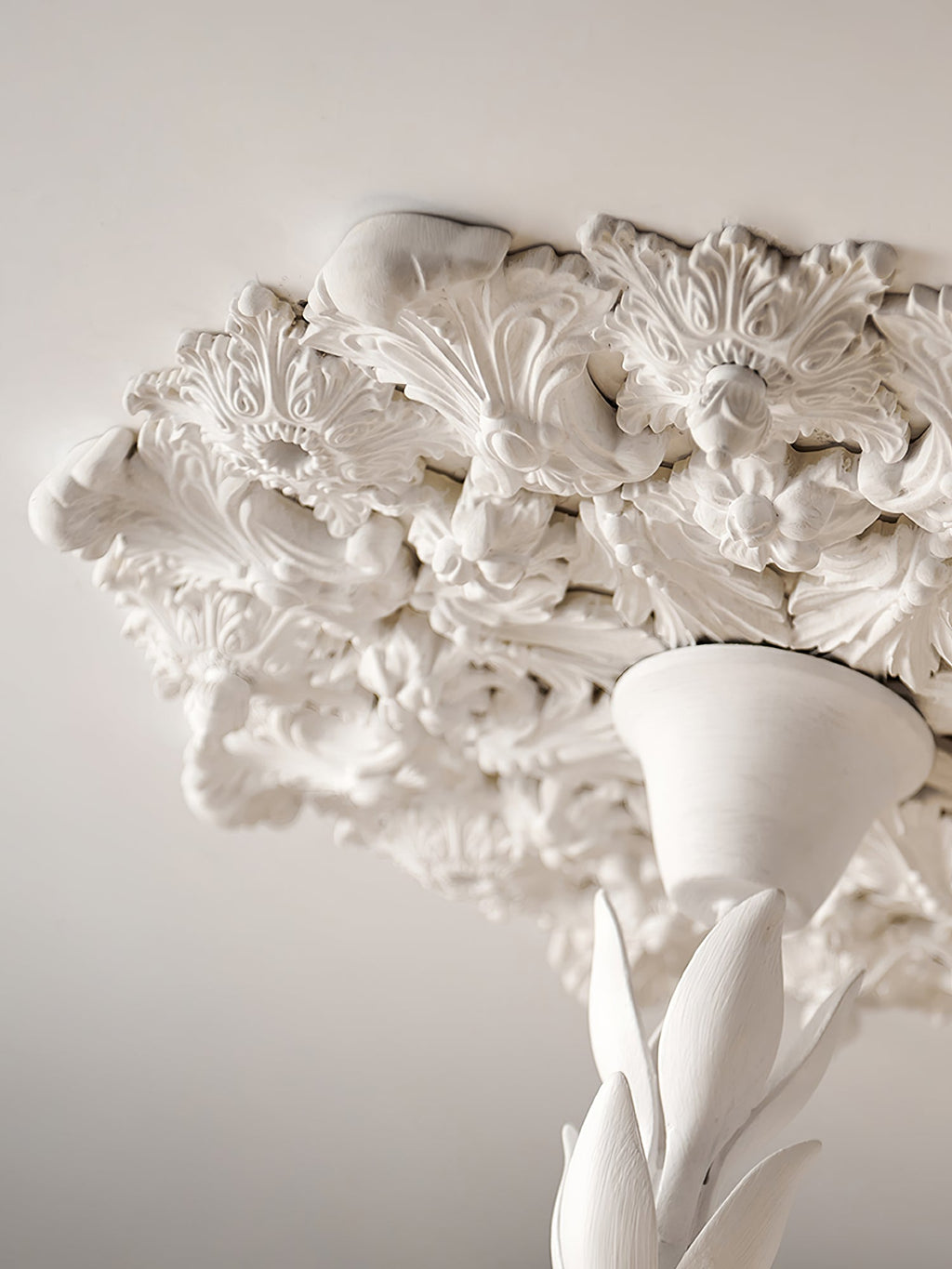 Underside of the plaster ceiling rose and the leaf-wrapped stem of this Clérachic ceiling light, seen from close below.