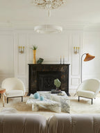 Distant view of this Clérachic ceiling light in a room with a black marble fireplace, white armchairs and a floor lamp.