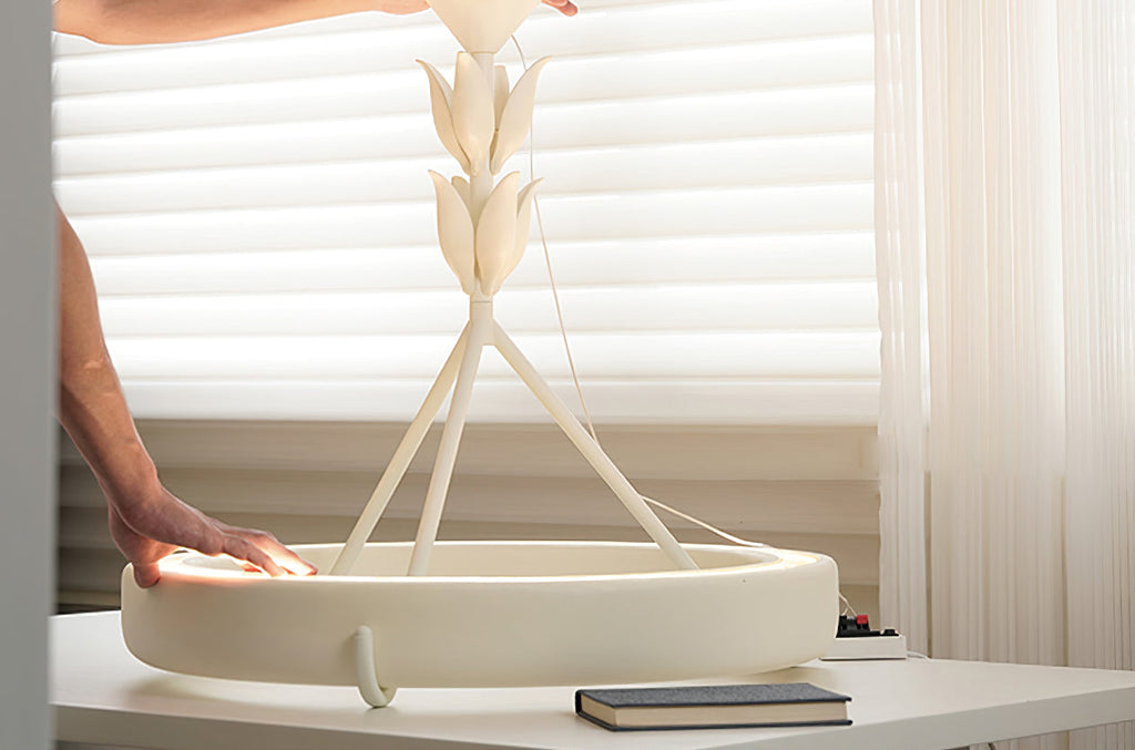 A hand rests on the plaster ring of this Clérachic ceiling light as it stands on a white table before sheer blinds.