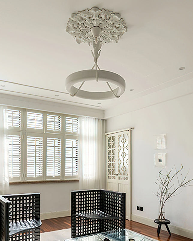 Clérachic ceiling light under a plaster rose in a bright room with shuttered windows, two black lattice chairs and a low branch vase.