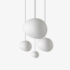 Four white satin glass pebble pendants from Clérachic at different heights, on a plain light backdrop.