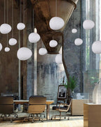 Clérachic white glass pebble pendants in many sizes hang above a meeting table and leather chairs in a loft space.