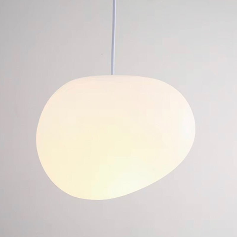 Close view of the glowing satin glass of a single Clérachic pebble pendant, with a soft, even warm light.