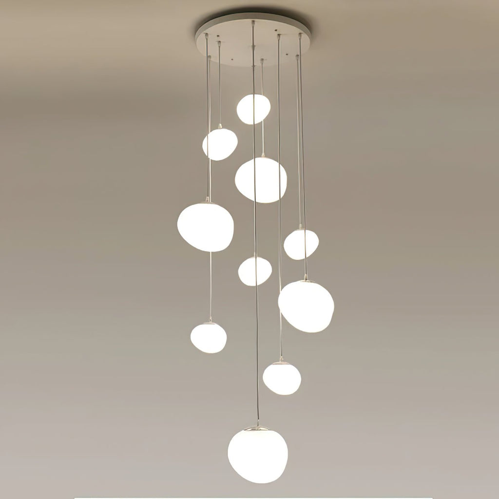 Cluster of nine Clérachic white glass pebble pendants hanging at staggered heights from one round ceiling canopy.