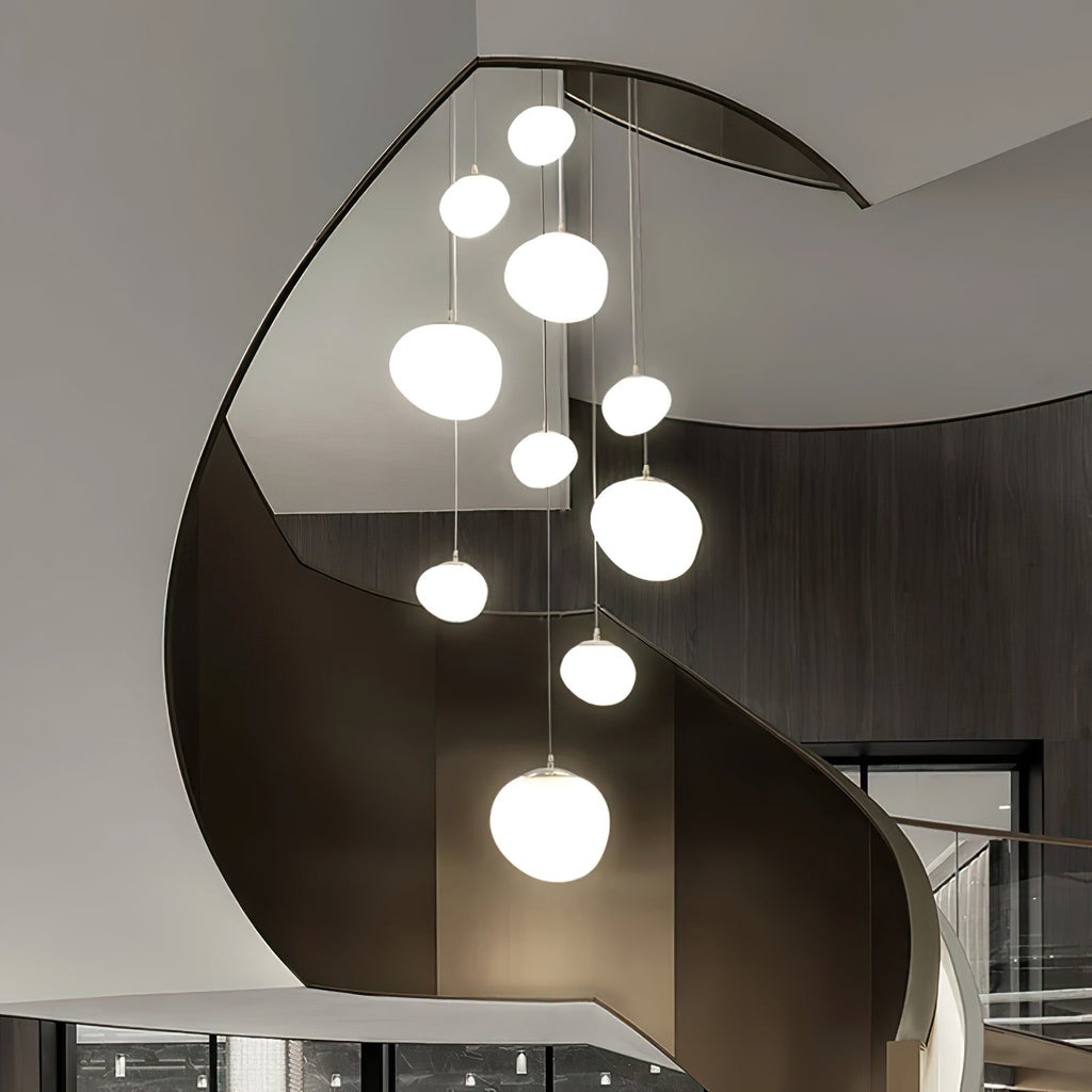Clérachic pebble pendants of different sizes spiral down a dark curved stairwell.