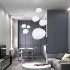 Clérachic white glass pebble pendants hang in a grey living area, with a white dining table and round coffee table.