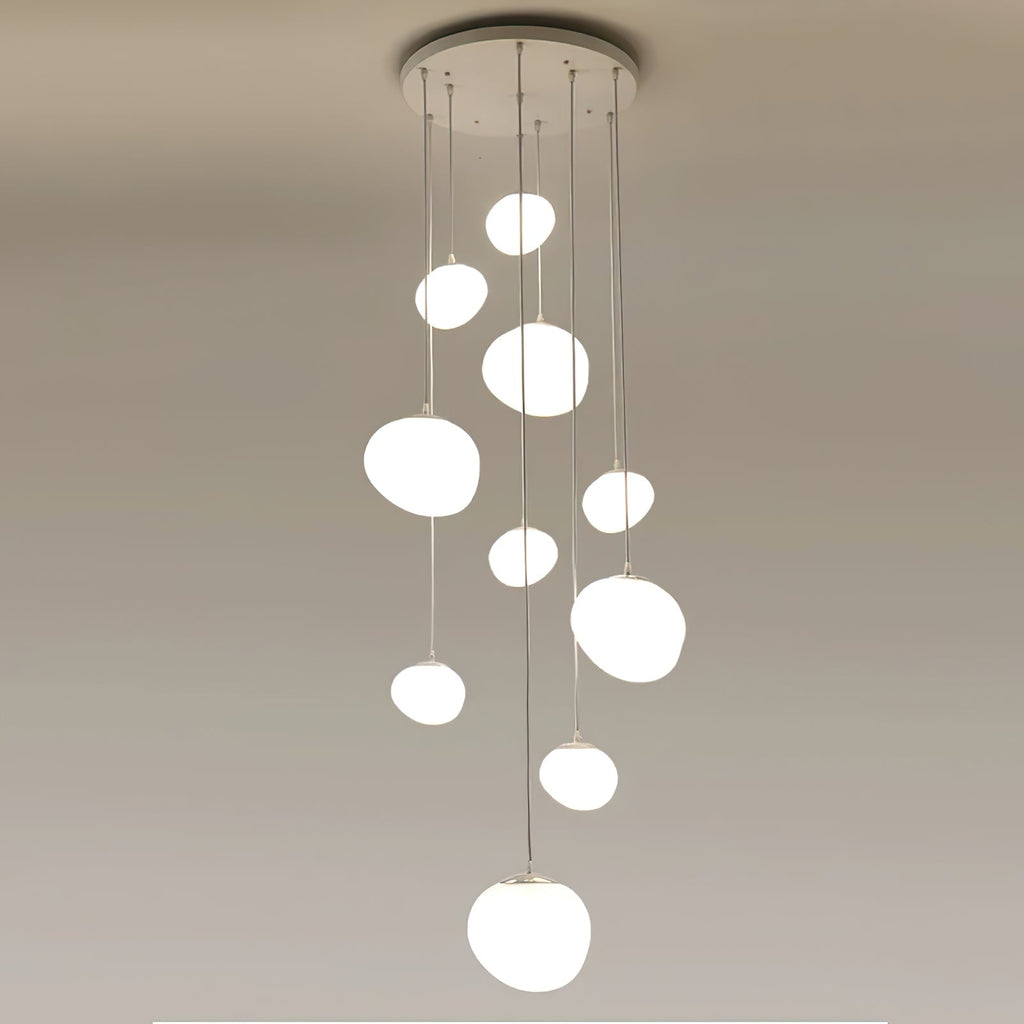 A tight cluster of Clérachic white glass pebble pendants hangs from a round white canopy on a plain ceiling.