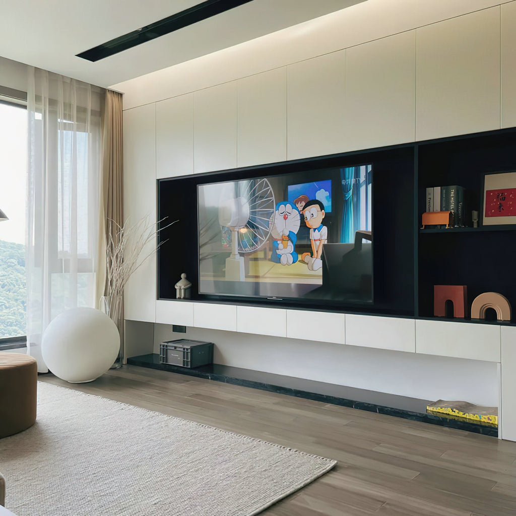 A white Clérachic sphere lamp on the floor in the corner of a bright living room, beside a pale curtain and a wall-mounted TV unit.
