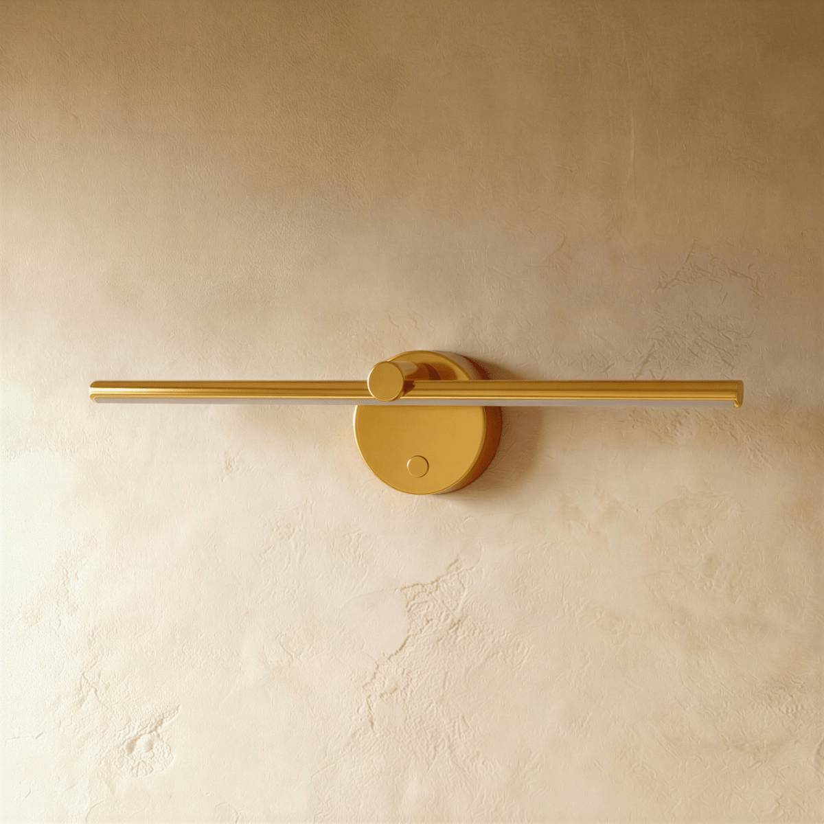 Clérachic wall lamp in brushed gold, the slender bar and round backplate shown unlit against a plaster wall.