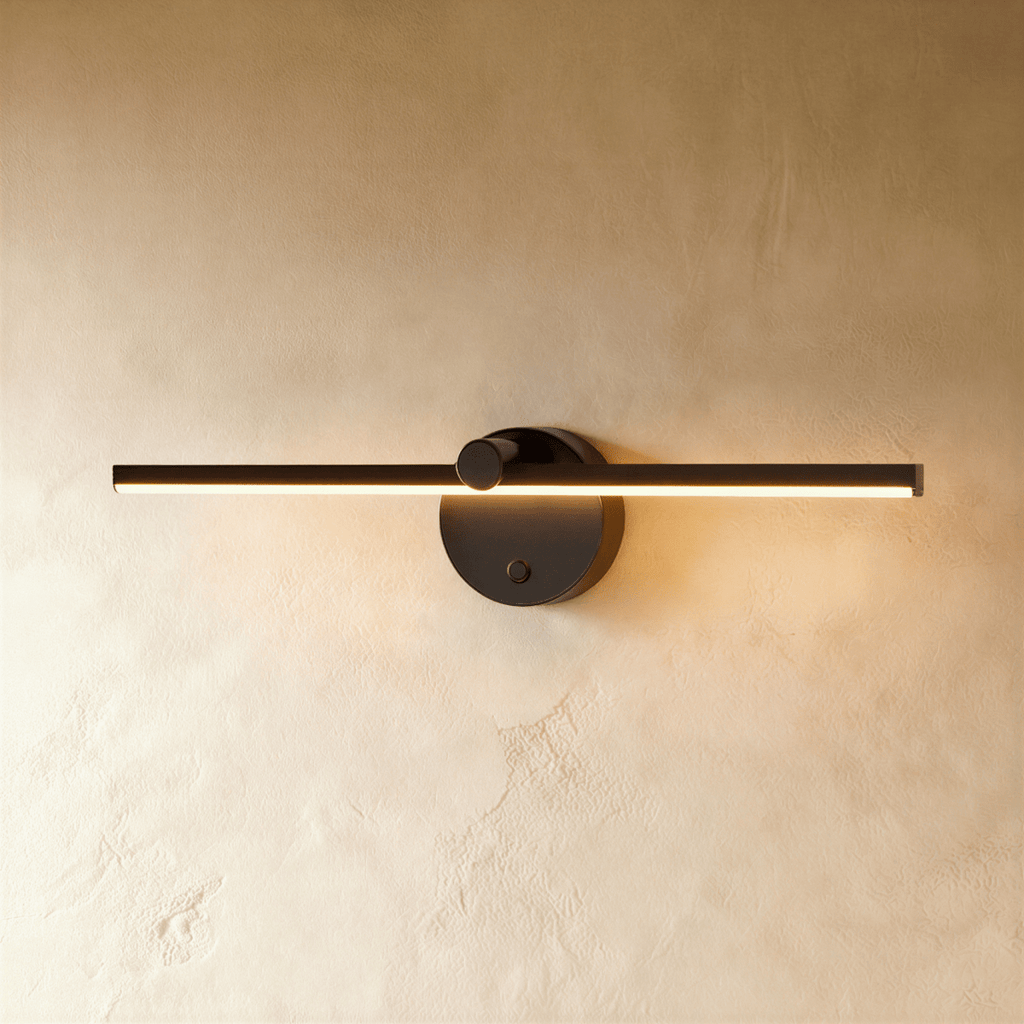 Clérachic wall lamp in matte black, its slim bar glowing warm white beside a round wall-mounted switch knob.
