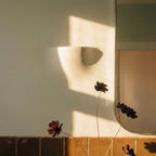 Sunlight casts the Clérachic trimless wall light's shape as a soft shadow beside a bathroom mirror.