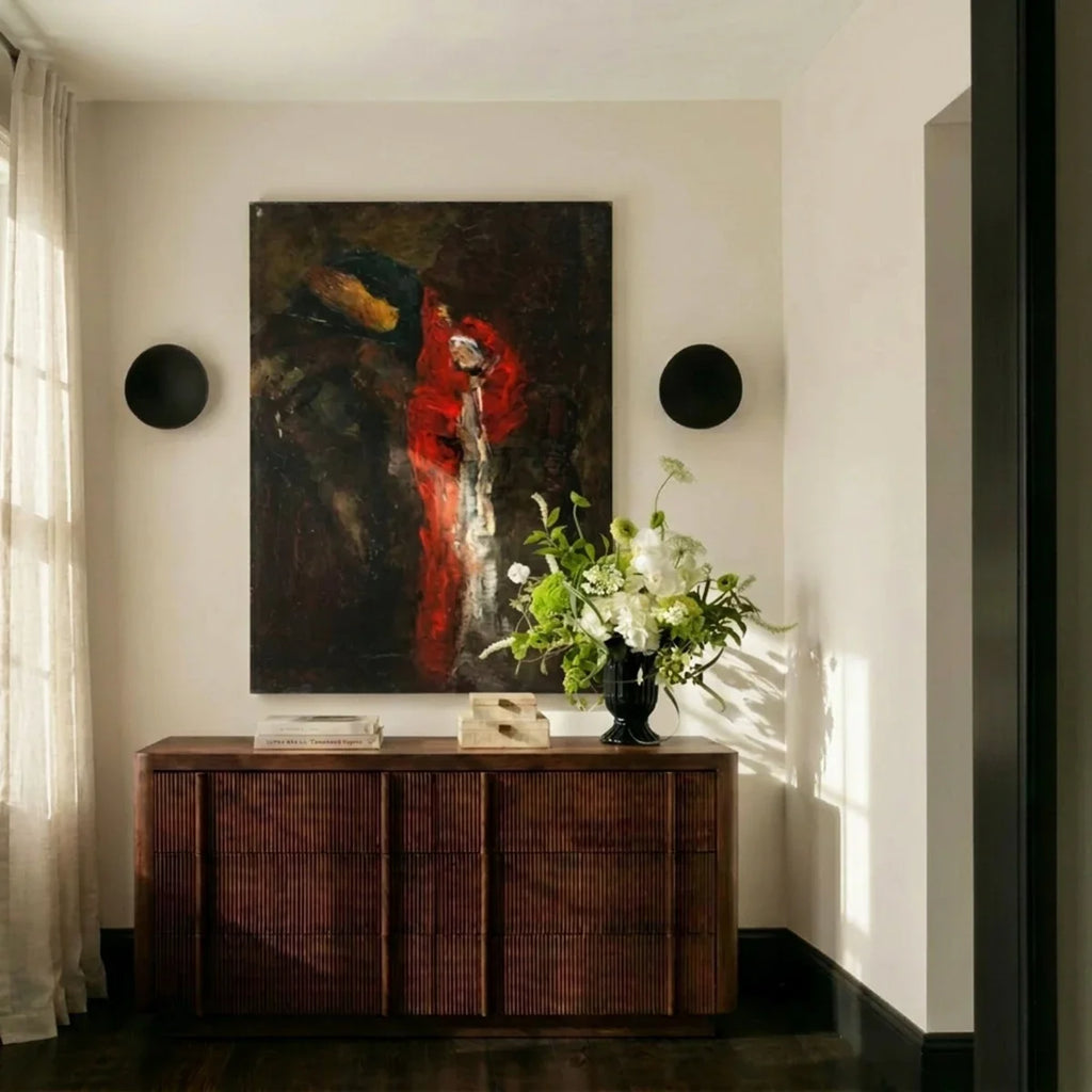 Clérachic's black wall lights frame an abstract canvas in a sunlit hallway beside a ribbed wood console table.