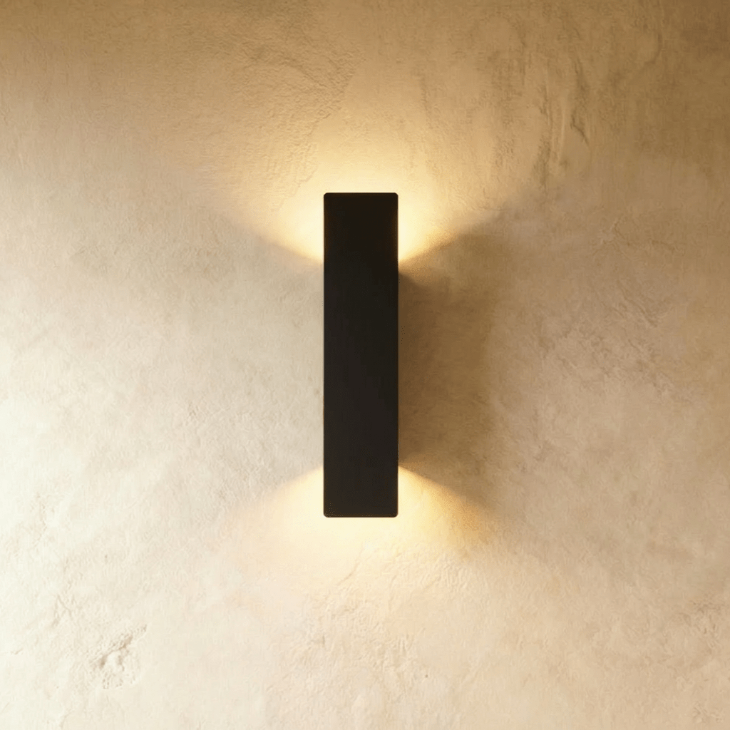 Clérachic black aluminium wall light in a taller bar profile, warm light washing up and down a plaster wall.
