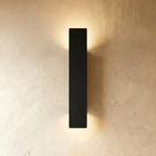 Clérachic black aluminium wall light in a 41 cm bar profile, casting warm light up and down a plaster wall.