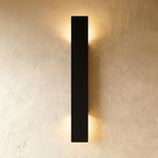 Clérachic black aluminium wall light in its tallest bar profile, light washing a plaster wall top and bottom.