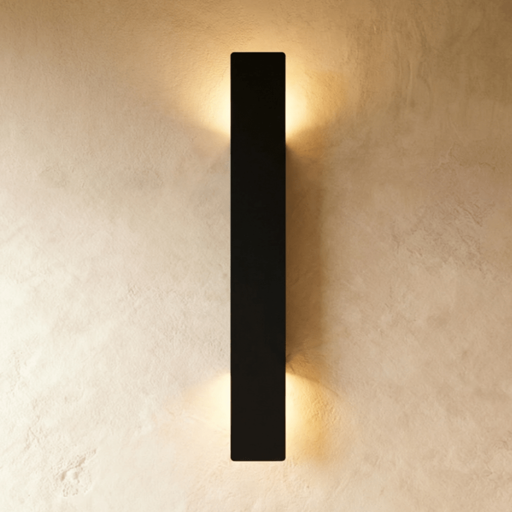 Clérachic black aluminium wall light in its tallest bar profile, light washing a plaster wall top and bottom.