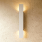 Clérachic white aluminium wall light in its tallest bar profile, light washing a plaster wall top and bottom.