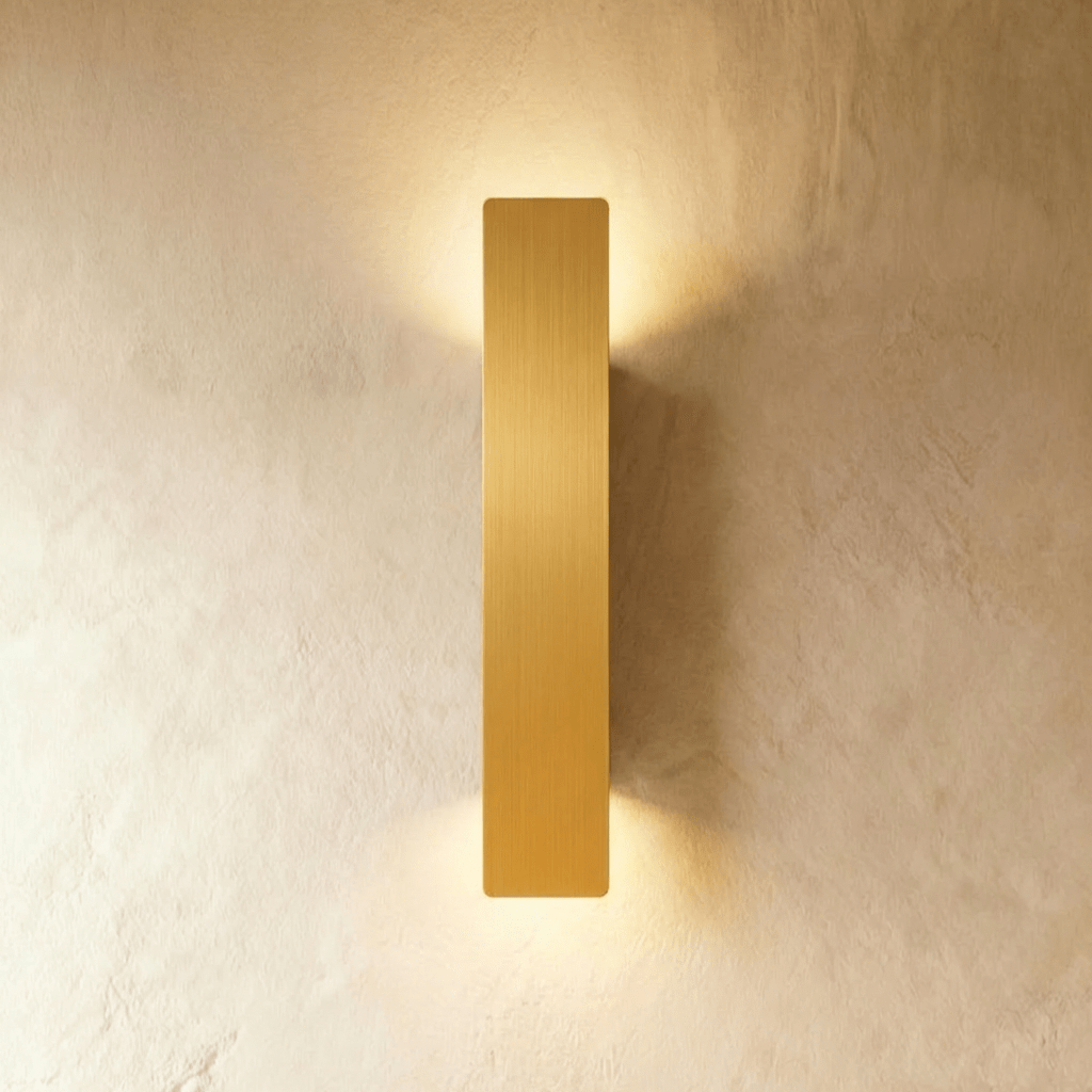 Clérachic brushed gold aluminium wall light in a longer bar profile, light washing a plaster wall top and bottom.
