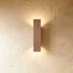 Clérachic coffee-toned aluminium wall light casts warm up-and-down light on a textured plaster wall.
