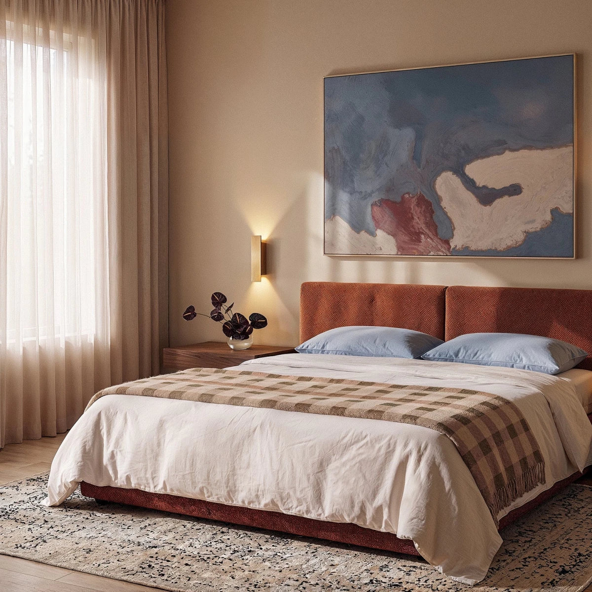 Clérachic gold wall light glows warm above a bedside table, lighting a bedroom with a rust velvet headboard.