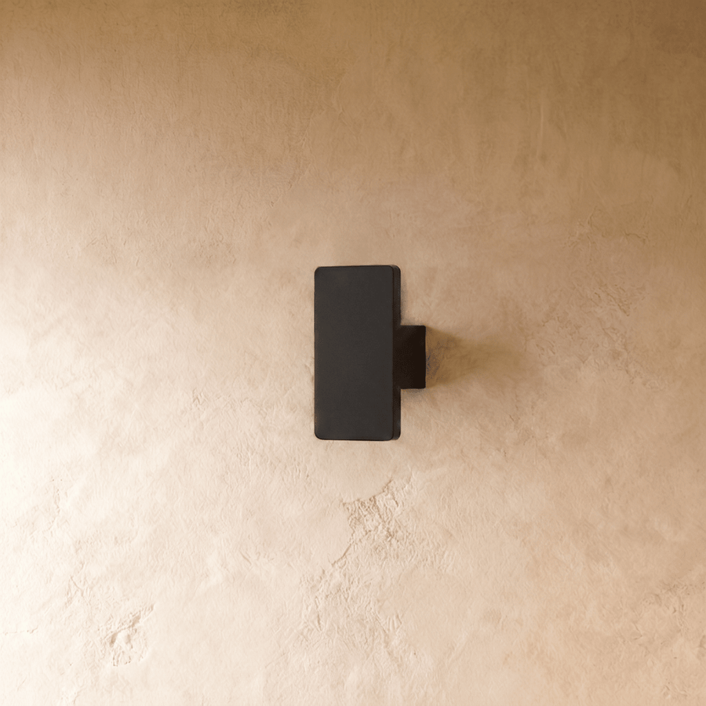 Unlit view of the Clérachic black wall light shows its compact rectangular block mounted flush to plaster.