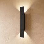 The longest Clérachic black wall light stretches down a plastered wall, its beams reaching far above and below.