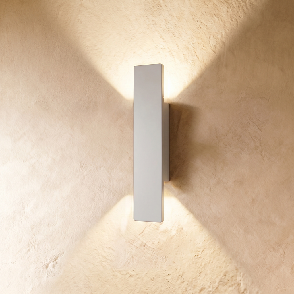 A taller Clérachic white wall light throws warm up-and-down beams across a textured plastered wall surface.