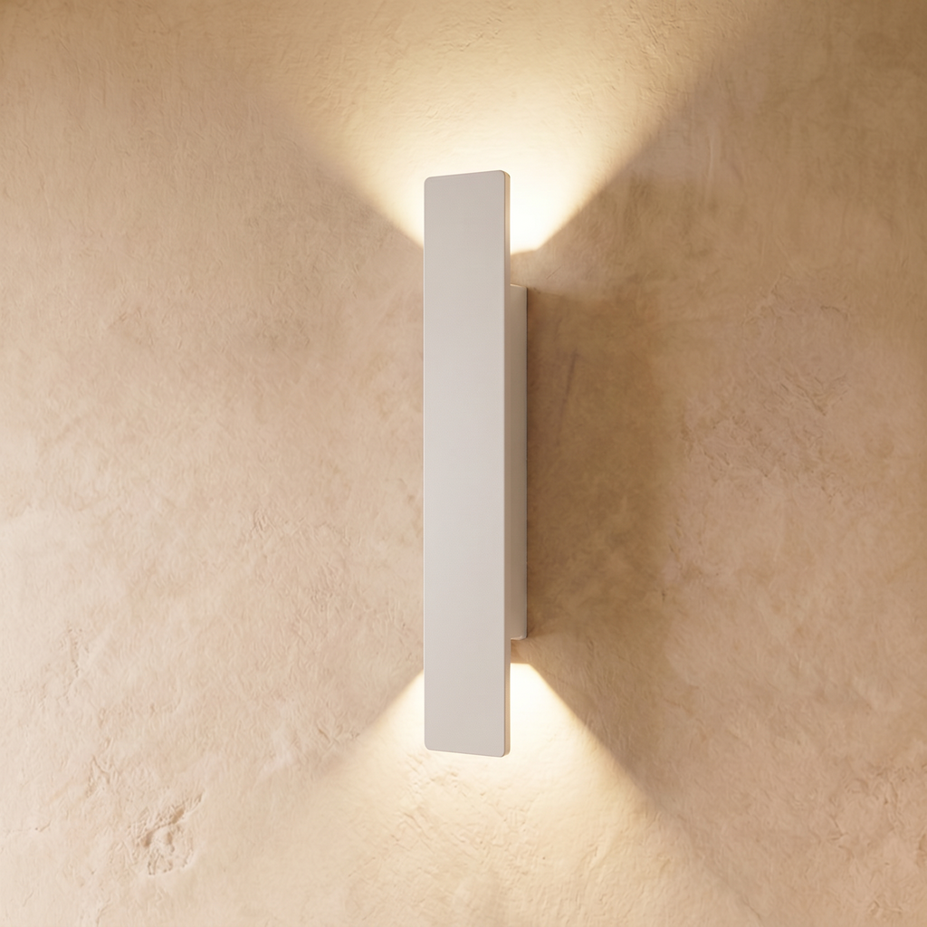 This longer Clérachic white wall light spans a wide plastered panel, warm light spreading above and below it.