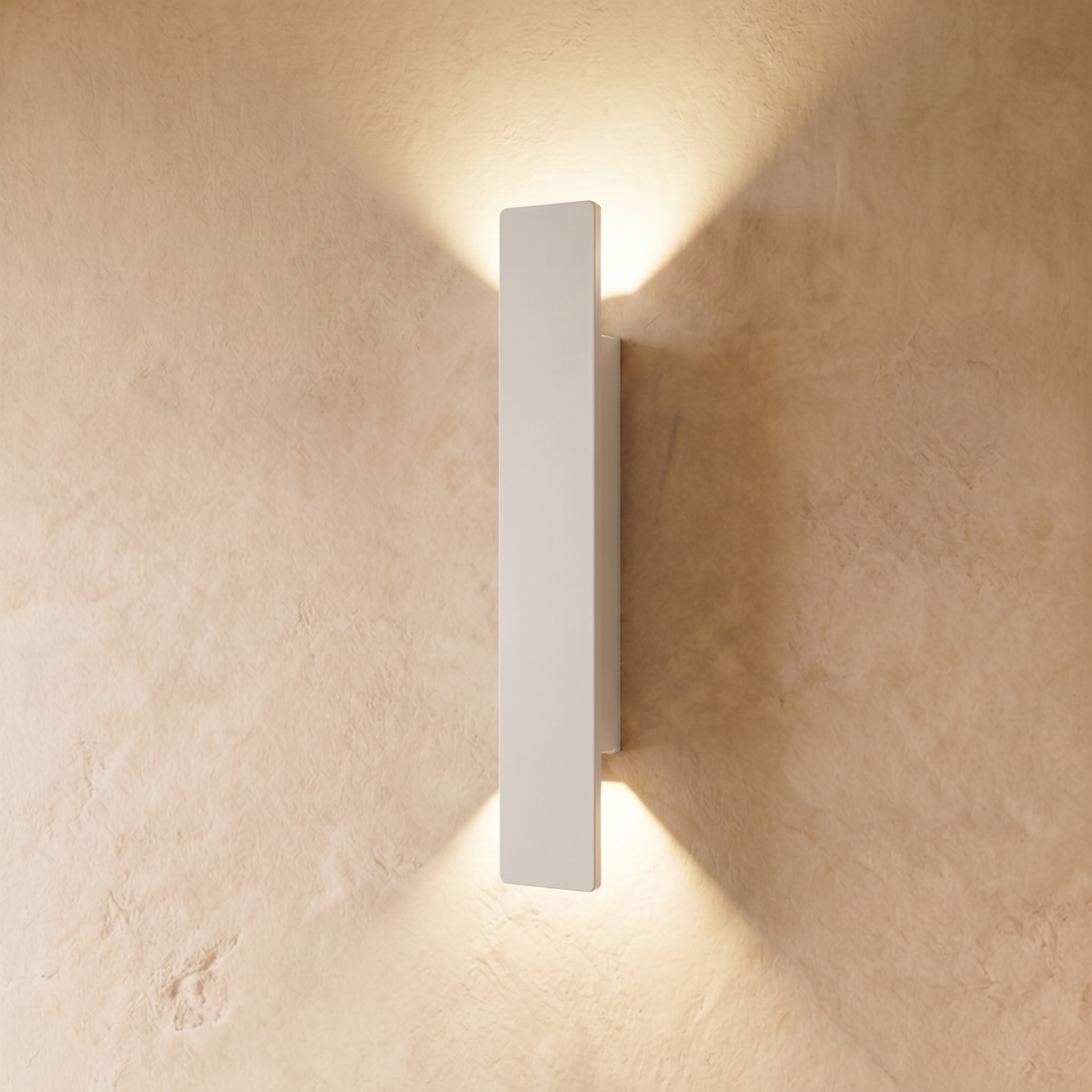 This longer Clérachic white wall light spans a wide plastered panel, warm light spreading above and below it.