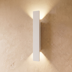 The longest Clérachic white wall light stretches down a plastered wall, its beams reaching far above and below.