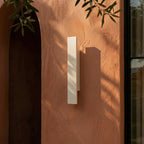 Close-up on the Clérachic white wall light shows its layered rectangular profile against terracotta plaster.