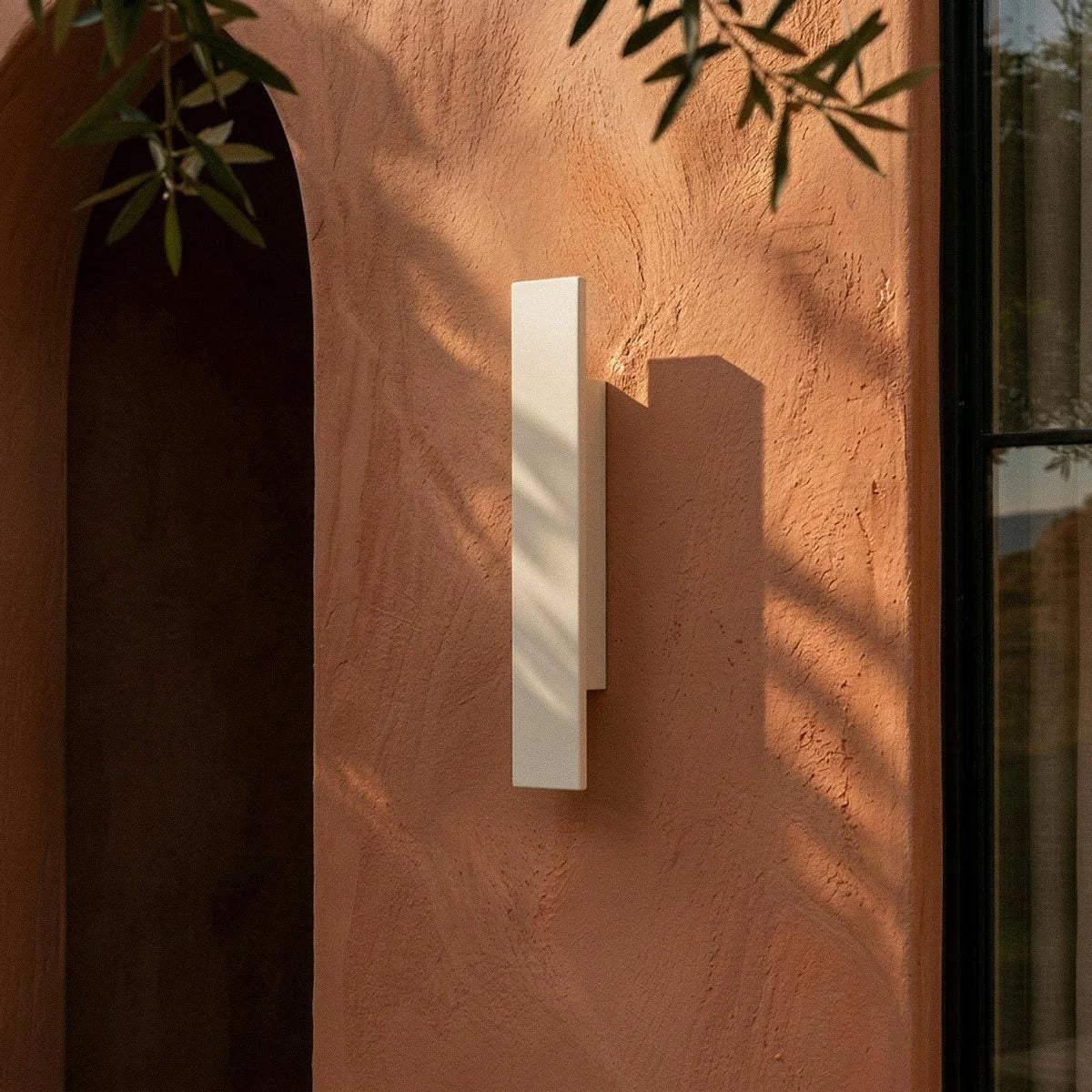 Close-up on the Clérachic white wall light shows its layered rectangular profile against terracotta plaster.