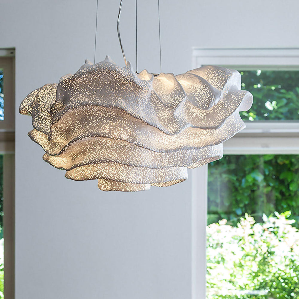Close view of the glittering perforated mesh on this Clérachic pendant, with leafy greenery through the window behind it.