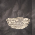 This Clérachic pendant lit from within, its fine mesh layers sparkling against a dark grey wall.